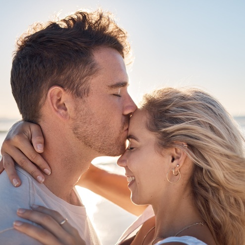 A man kisses his fiancée on the forehead, captured by a Maui engagement photographer.
