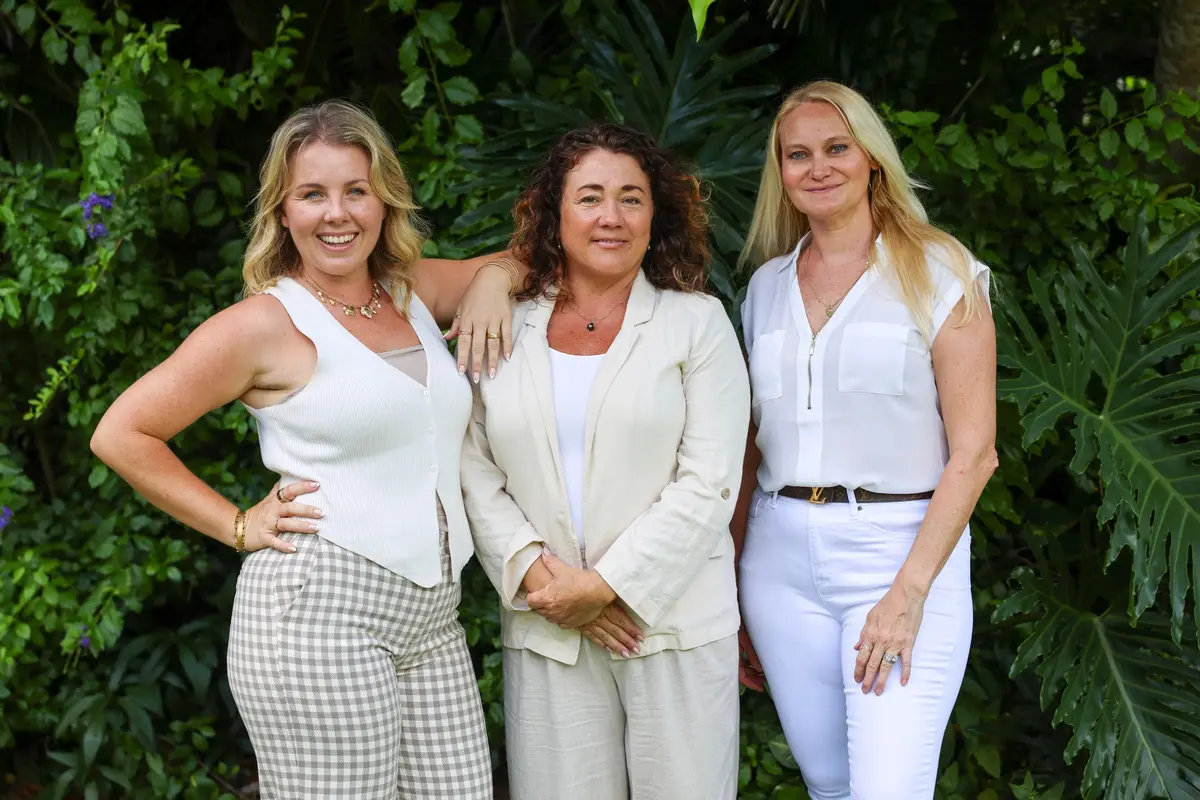 Three well-dressed women smile and pose during a business team photography session in Maui.