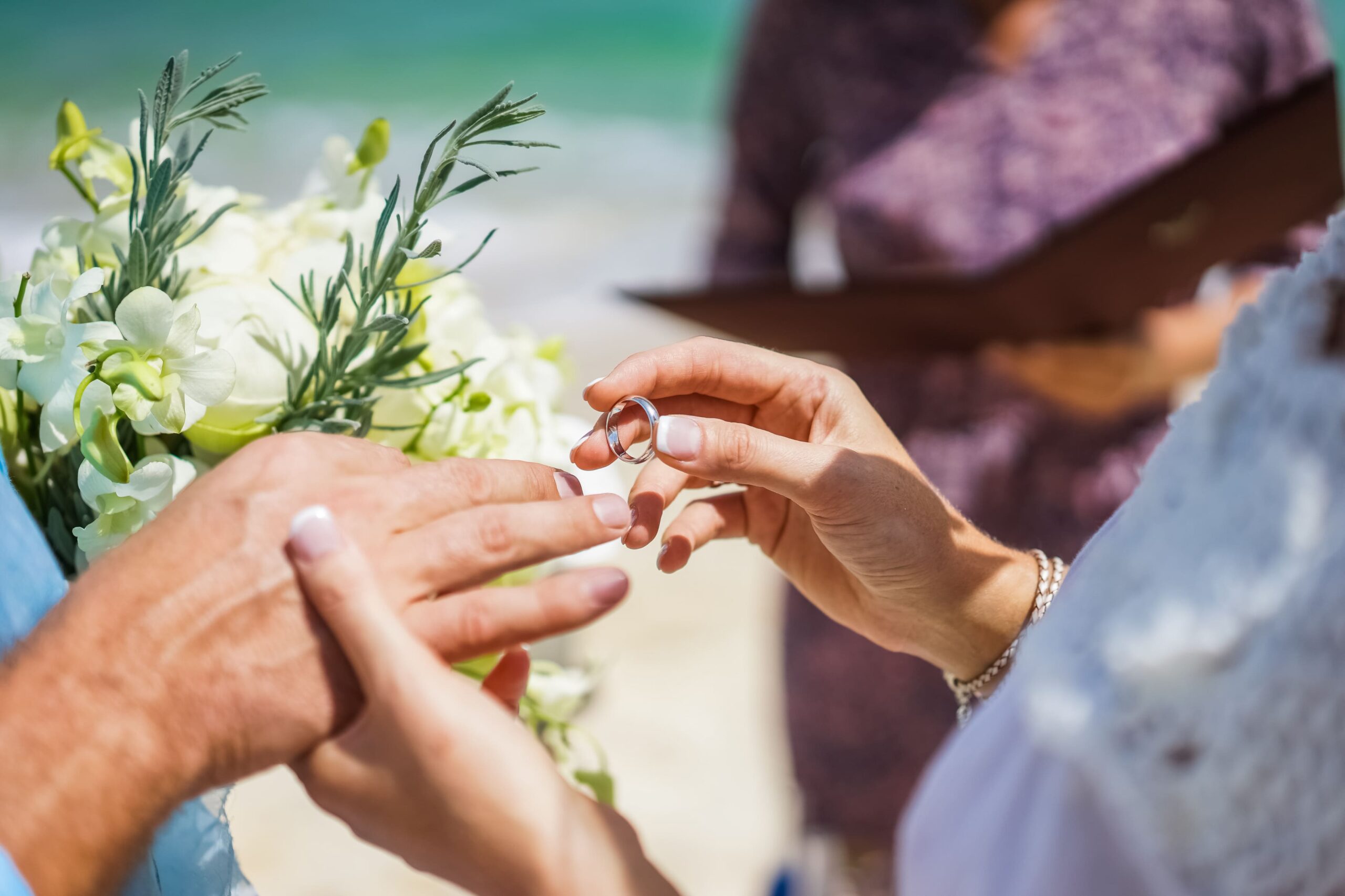 A bride places a wedding band on the groom during a West Maui wedding, close-up.<br />
