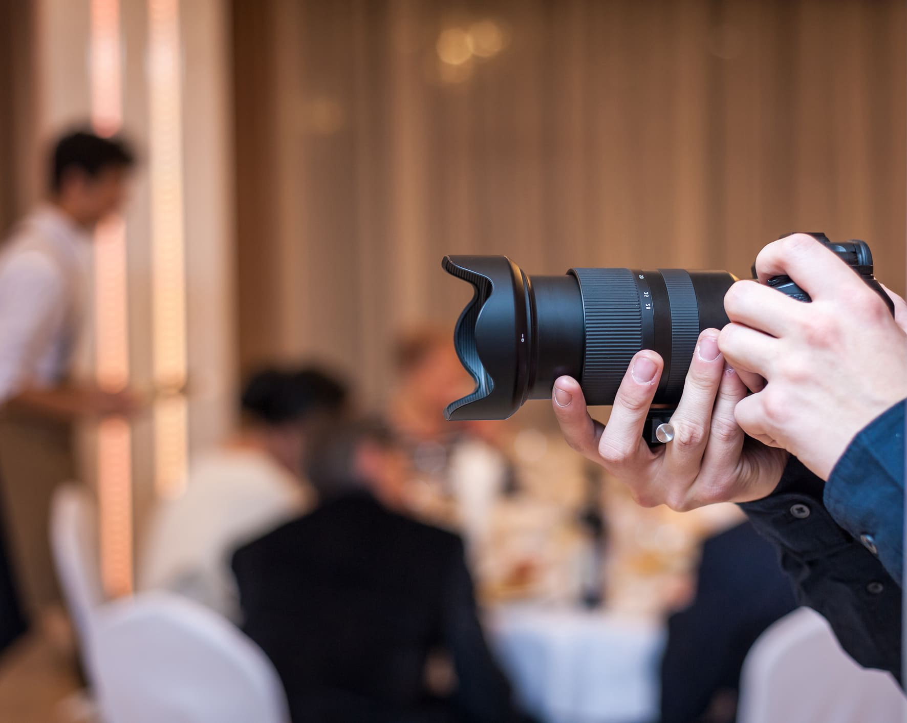 Videographer using a DSLR camera to film at a wedding reception.
