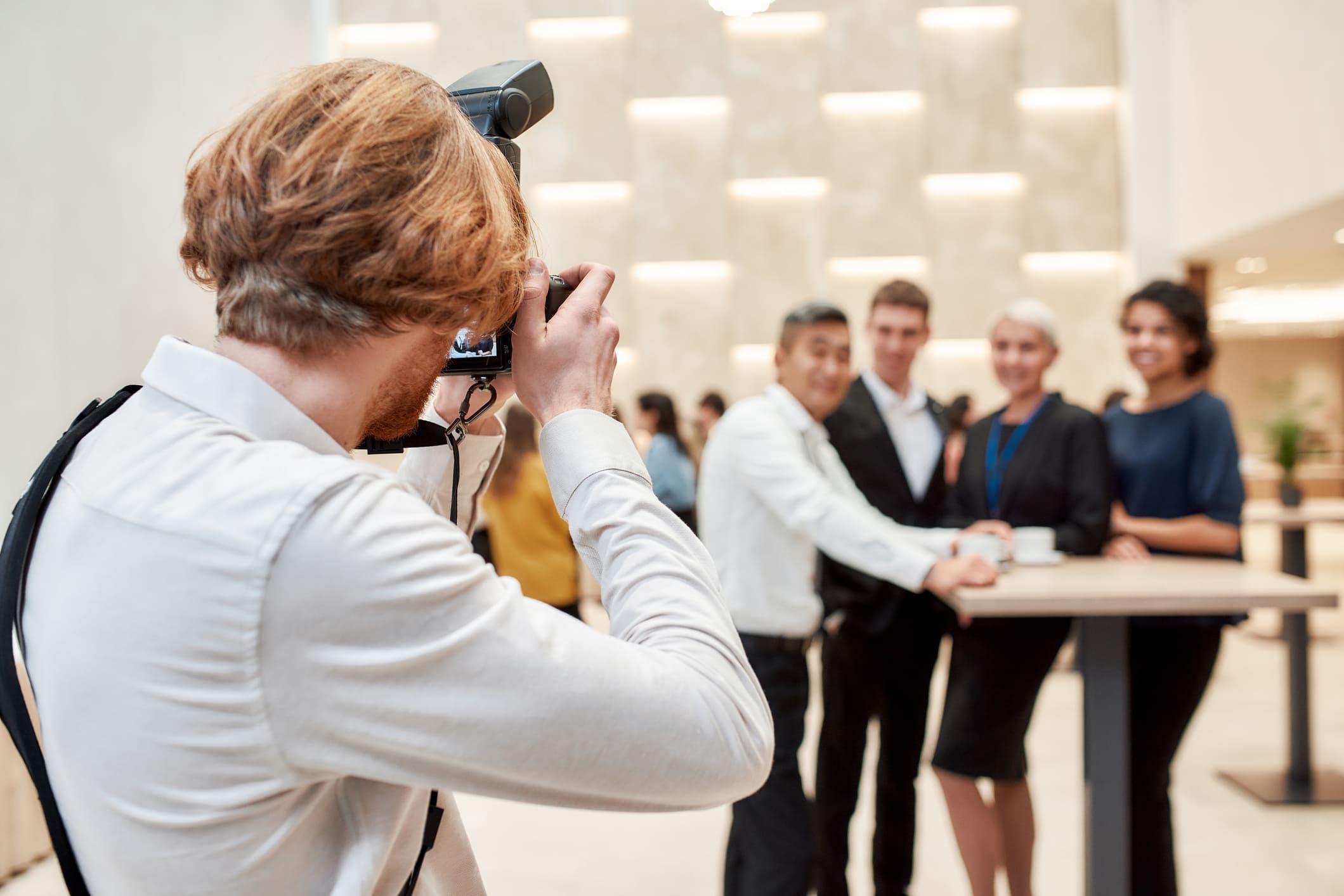Close-up of photographer taking photos and videos of businesspeople during an event.